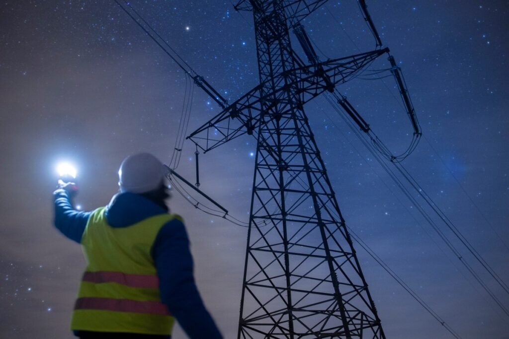 High-voltage engineer working on power lines at night.